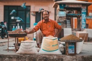 A street vendor in Jaipur selling grains and seeds on a busy day.